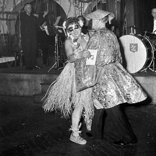 Two performers in playful, vintage costumes dancing on stage.