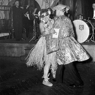 Two performers in playful, vintage costumes dancing on stage.