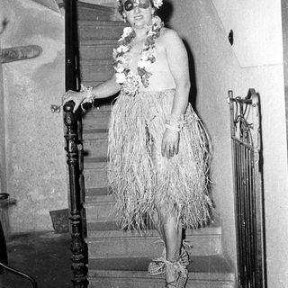 Woman in 1950s-style hula dress on staircase.
