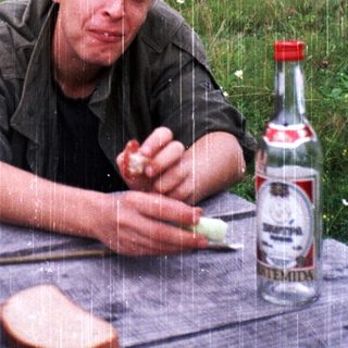 Man eating bread outdoors during light rain.