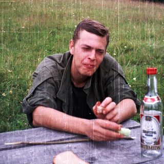 Man eating bread outdoors during light rain.