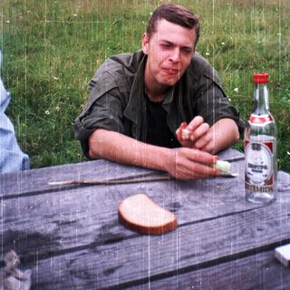 Man eating bread outdoors during light rain.
