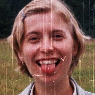 Woman smiling in light rain, holding water bottle.