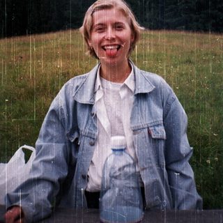 Woman smiling in light rain, holding water bottle.