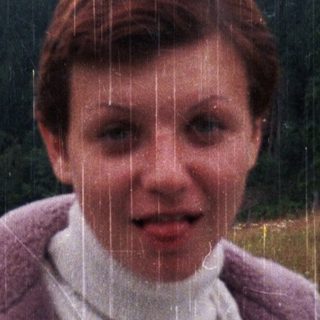 Person standing in rain with forest background.