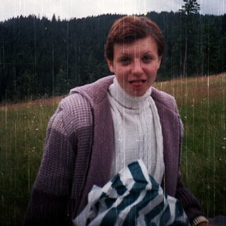 Person standing in rain with forest background.