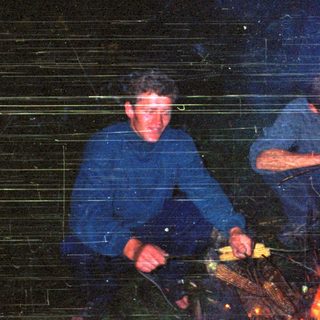 Three people roasting corn over an open fire.