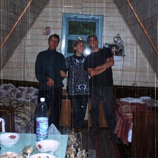 Three people standing indoors in a tent-like structure.