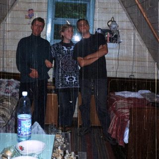 Three people standing indoors in a tent-like structure.