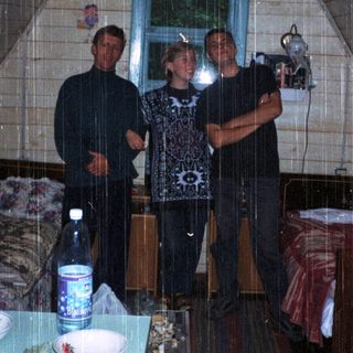Three people standing indoors in a tent-like structure.