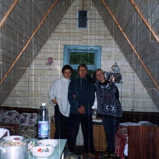 Three people posing indoors in a triangular igloo-style kitchen.