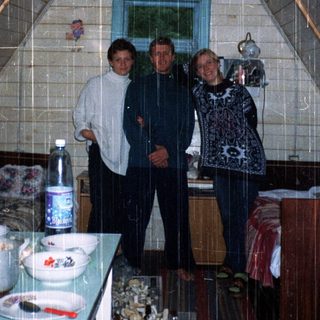 Three people posing indoors in a triangular igloo-style kitchen.