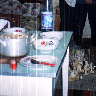 Three people posing indoors in a triangular igloo-style kitchen.