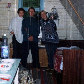 Three people posing indoors in a triangular igloo-style kitchen.