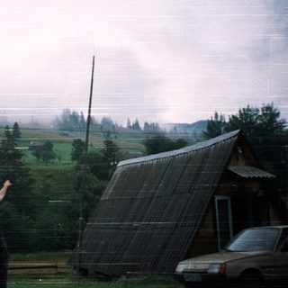 Man pointing near tilted solar panel in rural area.