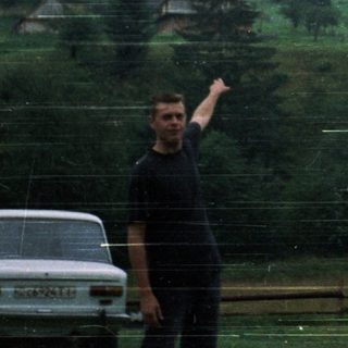 Man pointing near tilted solar panel in rural area.