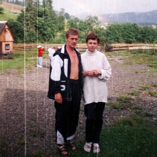 Two people standing outdoors in rainy countryside.