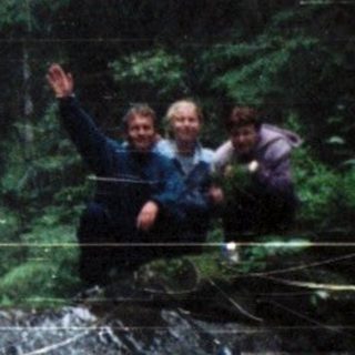 People ziplining over a cascading waterfall in forest.