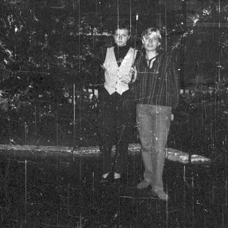 Two people standing under cascading water in indoor setting.