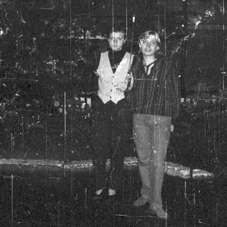 Two people standing under cascading water in indoor setting.