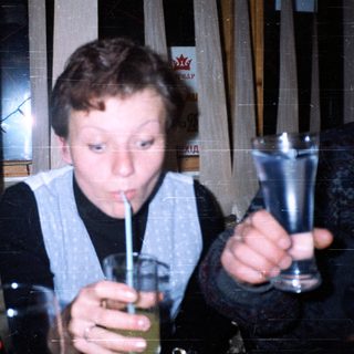 Boy drinking through a straw indoors.