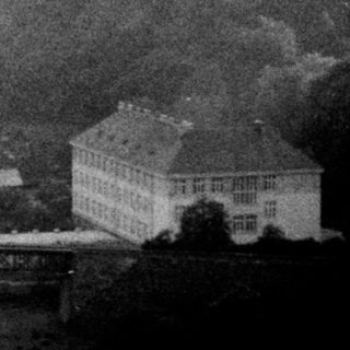 Historic bridge spanning river in hilly landscape.