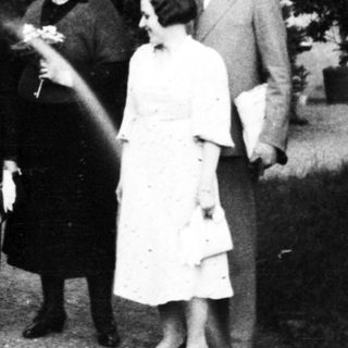 Family portrait with dog in early 20th-century garden setting.