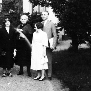 Family portrait with dog in early 20th-century garden setting.