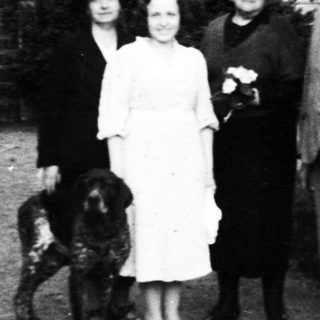 Family portrait with dog in early 20th-century outdoor setting.