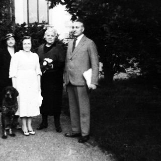 Family portrait with dog in early 20th-century outdoor setting.