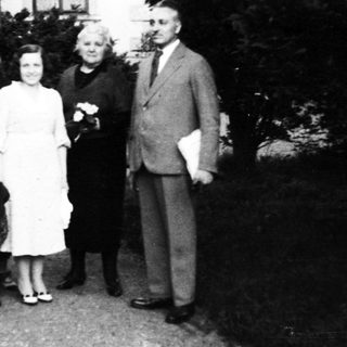 Family portrait with dog in early 20th-century outdoor setting.
