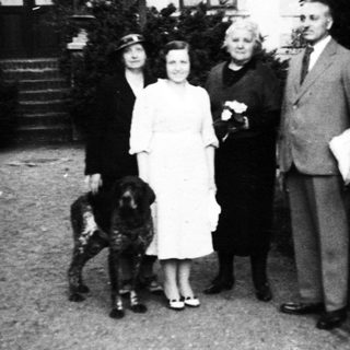Family portrait with dog in early 20th-century outdoor setting.