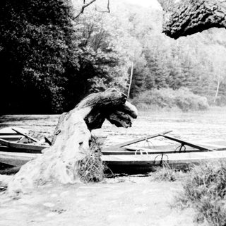 Boats moored near rocky riverbank with waterfall.