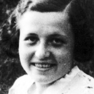 Young woman smiling outdoors in vintage dress.