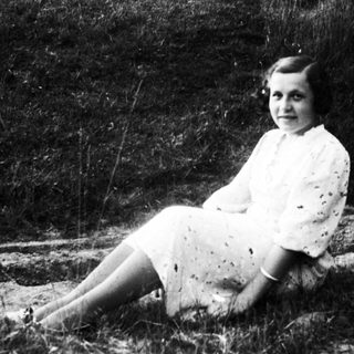 Young girl sitting outdoors in vintage dress.
