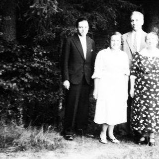 Four people posing outdoors in formal attire.