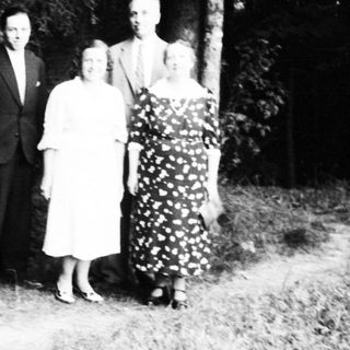 Four people posing outdoors in formal attire.
