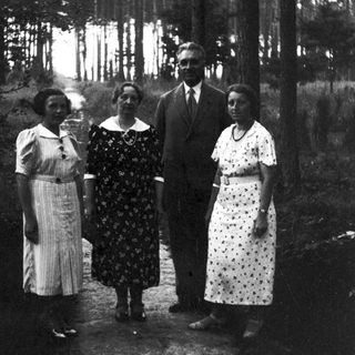 Four people posing outdoors in a wooded area.