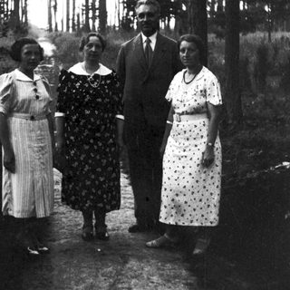 Four people posing outdoors in a wooded area.