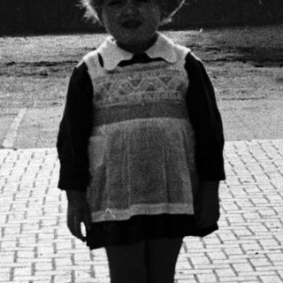 Child in vintage school outfit standing outdoors.