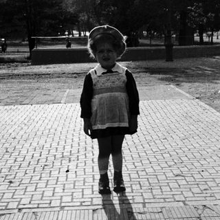 Child in vintage school outfit standing outdoors.