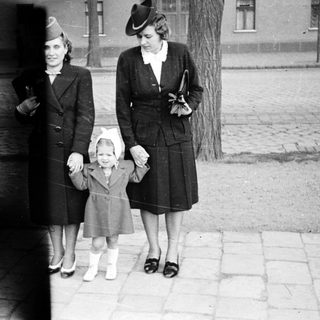 Three women in 1940s-era clothing walking outdoors together.