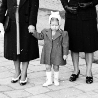 Three women walking outdoors holding hands.