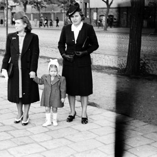 Three women walking outdoors holding hands.