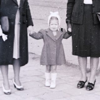 Three women walking together outdoors in 1940s-era clothing.