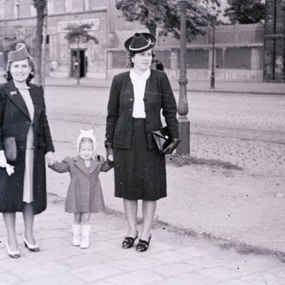 Three women walking together outdoors in 1940s-era clothing.