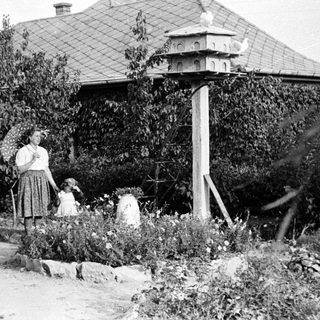 Vintage photo: Woman and child near traditional Japanese birdhouse.