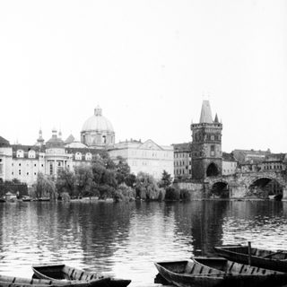 Historic bridge, river, and boats in Prague.