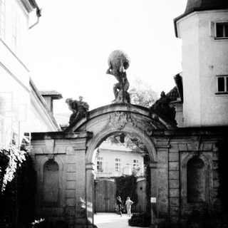 Elegant archway with classical statue and courtyard.