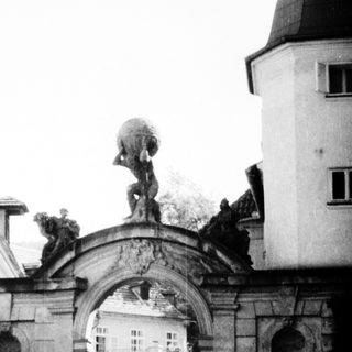 Elegant archway with classical statue and courtyard.